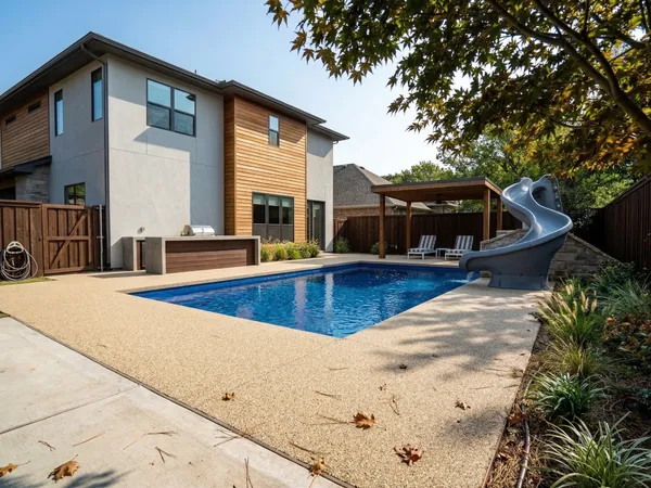 Modern backyard pool with a slide and tan TPV rubber deck surfacing
